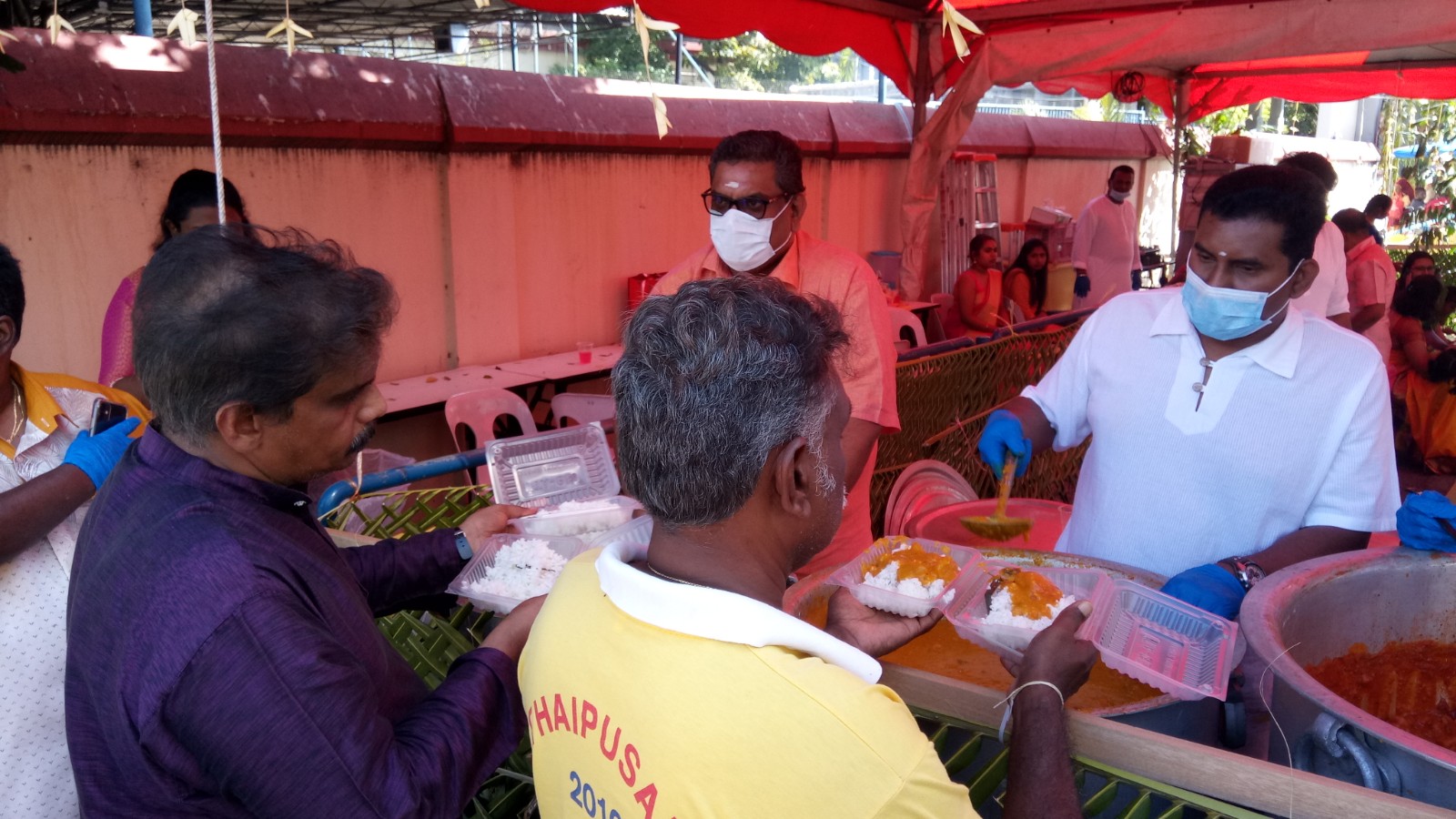 General Manager Prakash in face mask and his team members serving food to devotees.