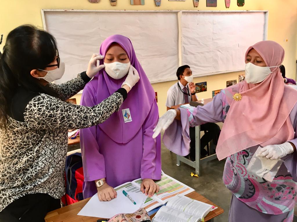 Yue helping another student with the face mask.